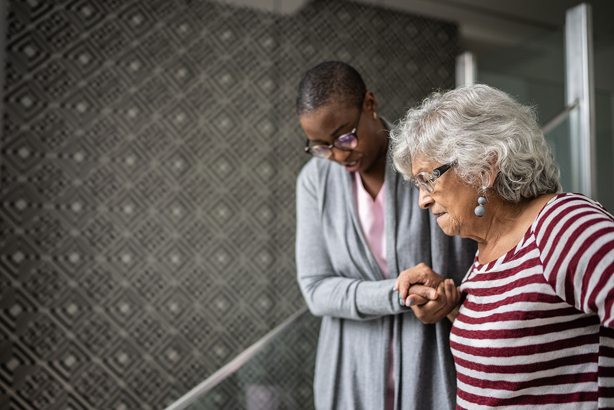 Woman assisting an elderly woman down the stairs