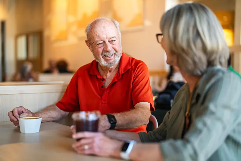 Elderly man talking with woman over coffee