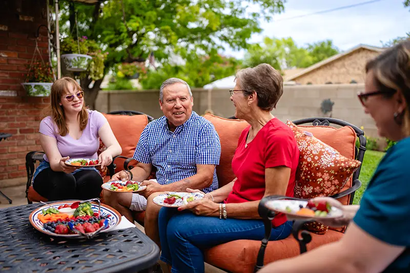 Elderly couple and younger woman sharing food outside