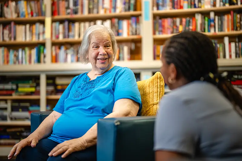 Woman in library talking to staff person.