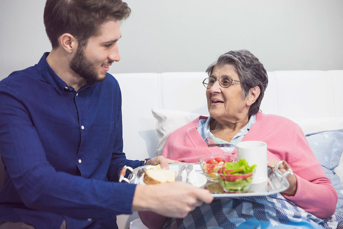 young-man-assisting-an-older-woman-with-a-food-tray young-man-assisting-an-older-woman-with-a-food-tray