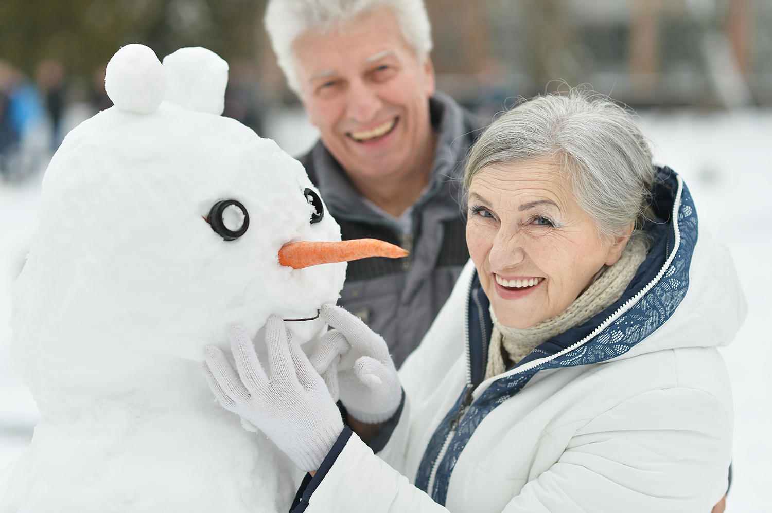 Older couple enjoying winter with a snowman
