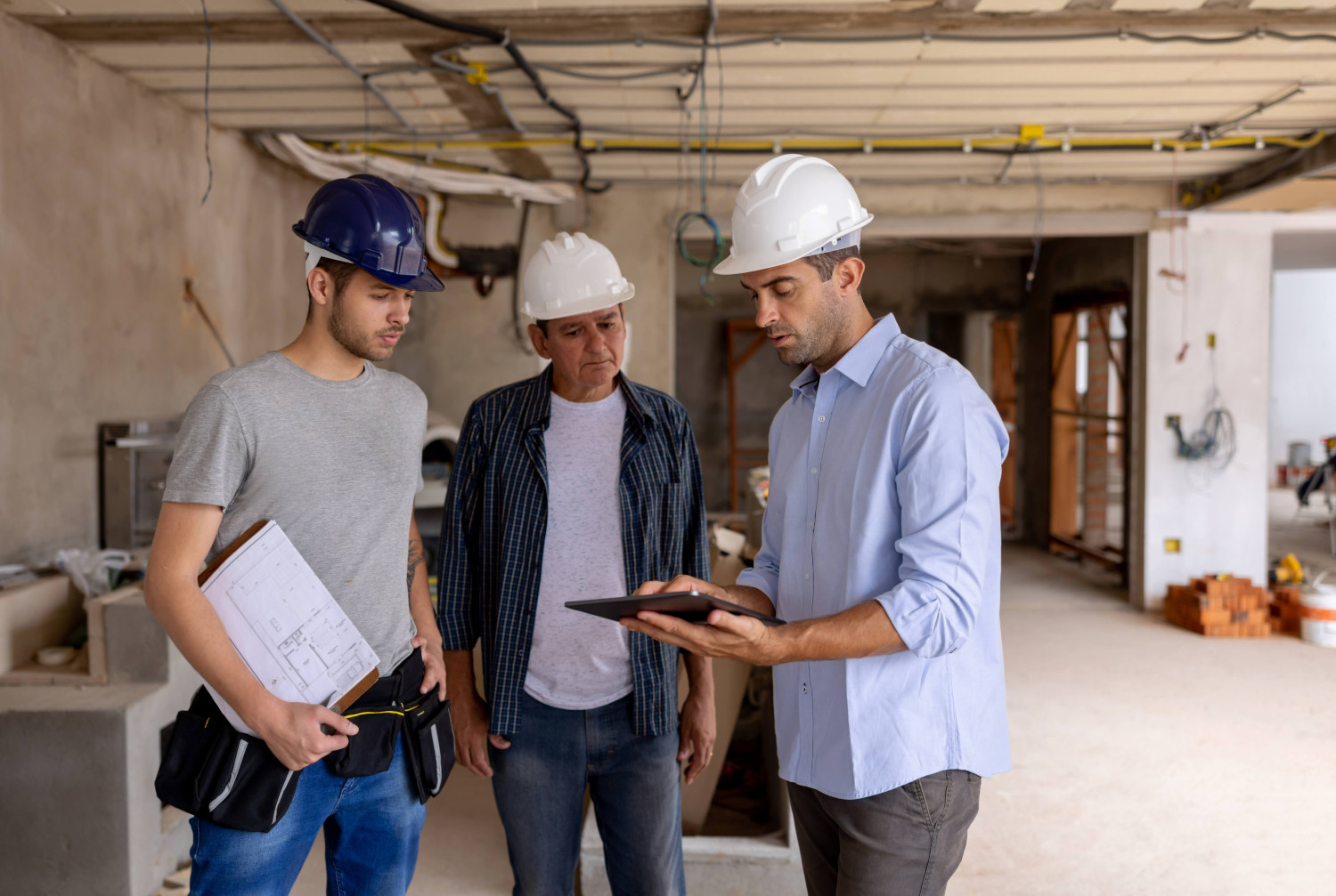Capital outlay three men at a construction site in hard hats looking at blue prints